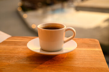 Cup of coffee next to a swimming pool