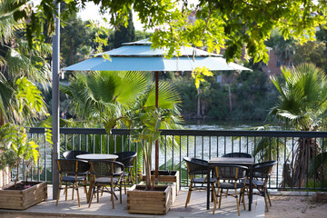 Garden set consisting of parasol, chairs and tables for a bar or terrace by the river in Seville, andalusia, Spain. Hospitality and catering concept.