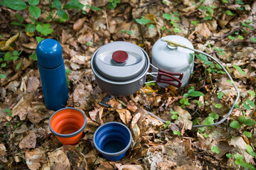 Coffee pot and metal cup on big stone against backdrop of mountain river. Coffee pot on stone plate over blurred nature background.