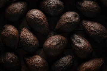 Old blackened spoiled brown avocados in - Beautiful dark black textured background, top view
