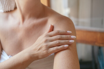  woman applies moisturizing cream or lotion after showering, daily body skin care routine 