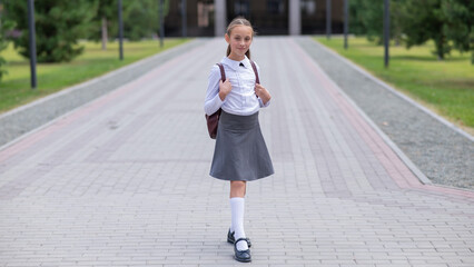 Portrait of caucasian schoolgirl in uniform and with backpack outdoors. 