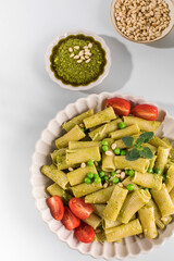 Delicious pasta with fresh basil pesto, green peas, cherry tomatoes and cheese.