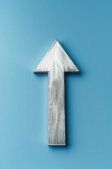 Fototapeta premium Metallic silver arrow pointing upward on a vibrant blue background, symbolizing direction, progress, and growth.