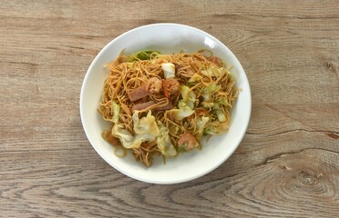 stir fried Hong Kong noodles cabbage and meat with slice bacon topping dry shrimp on plate