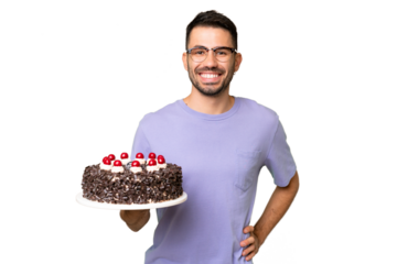 Young caucasian man holding birthday cake isolated on green chrome background posing with arms at hip and smiling