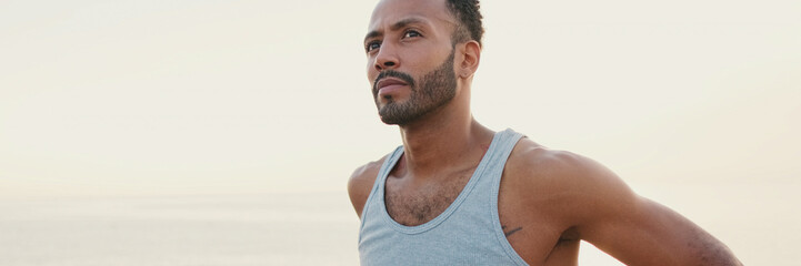 Obraz premium Young bearded male fit athlete standing on the embankment, panorama