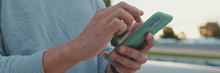 Close-up of hands, unrecognizable young man using mobile phone, panorama