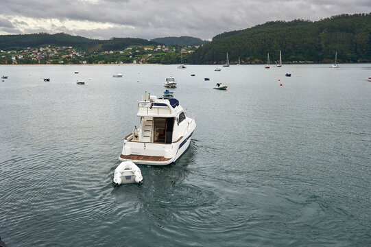 small pleasure yacht with inflatable boat tied to the bow in Cedeira Bay