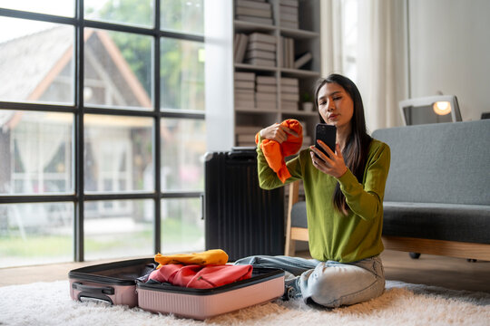 Young woman deciding what clothes to bring while packing suitcase for travel