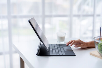 Woman working from home using tablet with keyboard and trackpad