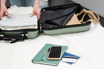 Unrecognizable woman packing suitcase for a solo traveling abroad. Summer vacation. Traveling overseas.