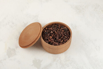 Cocoa nibs in wooden bowl. Crunchy pieces of peeled, crushed and lightly roasted cocoa beans with pleasant chocolate bitterness. Sugar-free product.