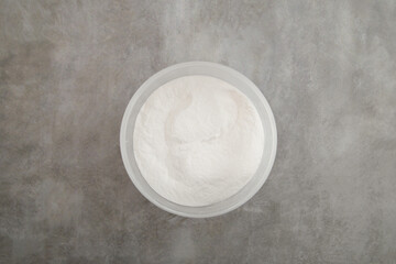 Powder of Microbial transglutaminase also called microbial TGase, Tgase, or meat glue in plastic box, top view. Food additive is used in the production of processed meat and fish products.