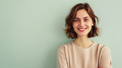 Obraz premium Portrait of a Radiant 30 year old Woman with a Sweet Demure Smile and Elegant Style, Short Brown Hair, Green wall with copy space