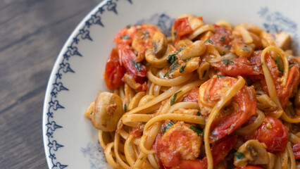 Close-up of a plate of tomato and shrimp pasta with mushrooms
