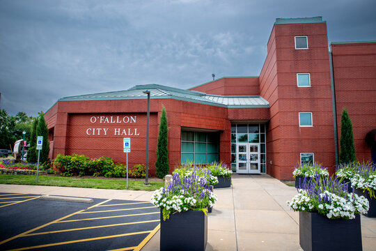 Saint Clair County, IL--July 27, 2024; Brick building marked to identifying it as the Ofallon Illinois City Hall building with cloudy sky background in summer.