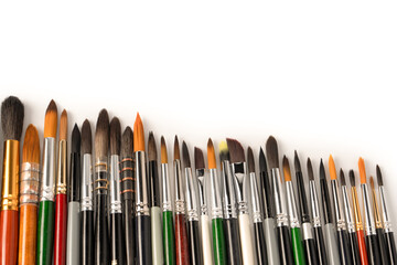 Mix of paint brushes in a row isolated on a white background.