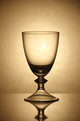 the glass is beautifully empty for drinks and alcohol. shot against a light yellow background, silhouetted in dark spots