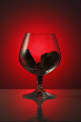 the glass is beautifully  for drinks and alcohol. shot against a light red background, silhouetted in dark spots