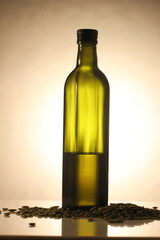 pumpkin seed oil in a dark green bottle and a scattering of seeds in a row. taken in close-up on a...