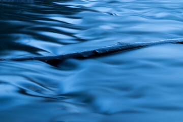 Wood log in creek, smooth water in long exposure