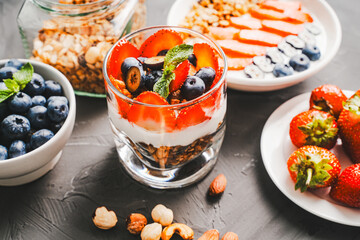 Light berry dessert with Greek yogurt and granola, parfait with fresh berries strawberries and blueberries on a gray table. Selected focus.