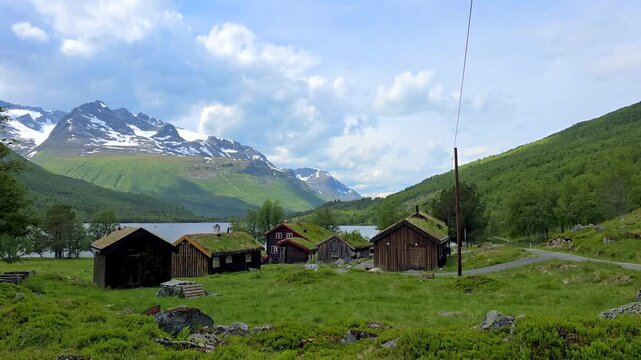 Aerial footage captures remote mountain villages with green roofed houses, fields, lakes, and picturesque rural landscapes, showcasing serene rural life, Innerdalen valley Norway