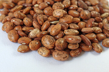 Vibrant image of pinto beans arranged on white backdrop, showcasing rich brown and beige hues. Nutritious, versatile, and visually striking