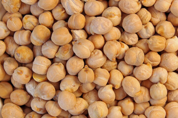 Numerous chickpeas are laying on a flat surface, creating a filled frame background texture