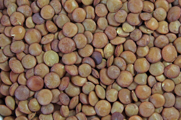 Brown lentils spread out, creating a textured background for food photography. Healthy, versatile, and popular in vegetarian and vegan diets, lentils are a staple ingredient in many cuisines