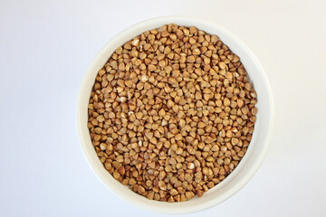 White bowl filled with nutritious buckwheat grains on a clean background, ideal for healthy diets. Perfect for promoting plant-based lifestyles, white background