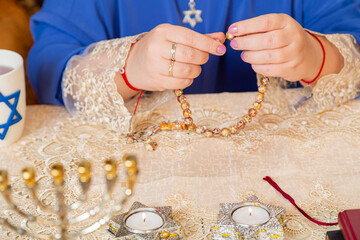 The Jewish man's hands are fingering his rosary at the table