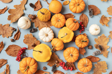 Fototapeta premium Autumn background from fall leaves, pumpkins and seasonal decorations on turquoise table top view.