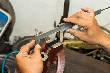 Close up scene the machine operator measuring dimension of cast iron parts by Vernier caliper.