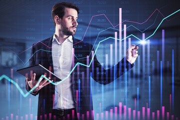 Businessman analyzing financial data on a virtual screen, holding a tablet.