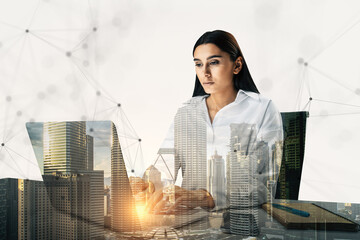 Double exposure of a businesswoman working on a laptop with a cityscape overlay.