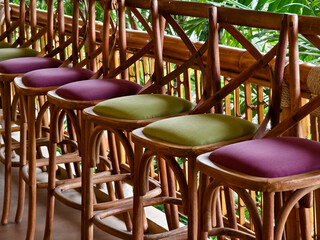 A row of chairs made of wood with cushions in purple and green colors