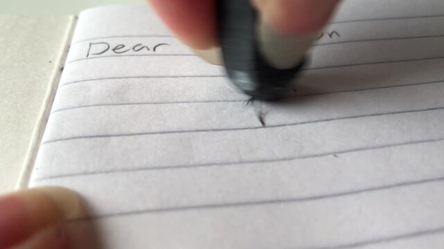 closeup of a hand erasing the words &ldquo;I love you&rdquo; from a letter
