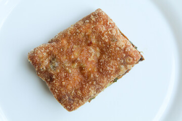 One piece cut of Martabak Telur. Pancake with egg, flour, and leek slices, snack from Indonesia. Isolated on white background