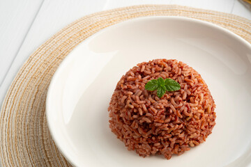 Cooked Thai Organic Red Jasmine Rice in white plate.semi-milled rice.including fiber, B vitamins and magnesium, offering a richer nutritional profile than traditional white rice.