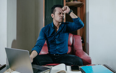 Stressed, tired and frustrated business man with headache at night from burnout or making mistake...