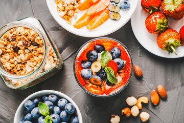 Gourmet breakfast: berry parfait of strawberries, blueberries and granola with delicate Greek yogurt, mascarpone and whipped cream on a gray background. Selected focus.