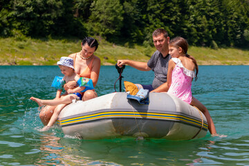 Obraz premium Father and mother with kids sitting on a boat on the river in the summer