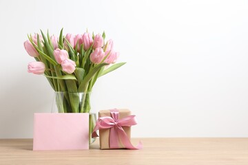 Beautiful fresh tulips in a vase with gift box and paper card