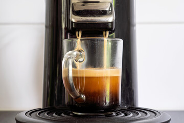 glass cup with freshly brewed coffee from coffee pad machine