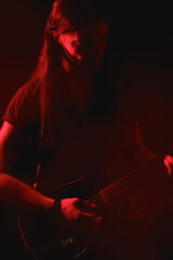 Long-haired Electric Guitarist Playing Under Red Light