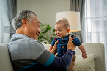 An older man is holding a baby in his arms. Concept of warmth and happiness between the two