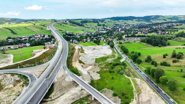 New fragment of highway under construction on Zakopianka road, Poland, over Klikuszowa village. Entrance and exit ramps, traffic circle. State in July 2024. Aerial view. Old road on the right