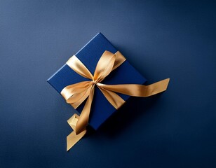 Dark blue gift box with gold satin ribbon on dark background. Top view of birthday gift with ribbon